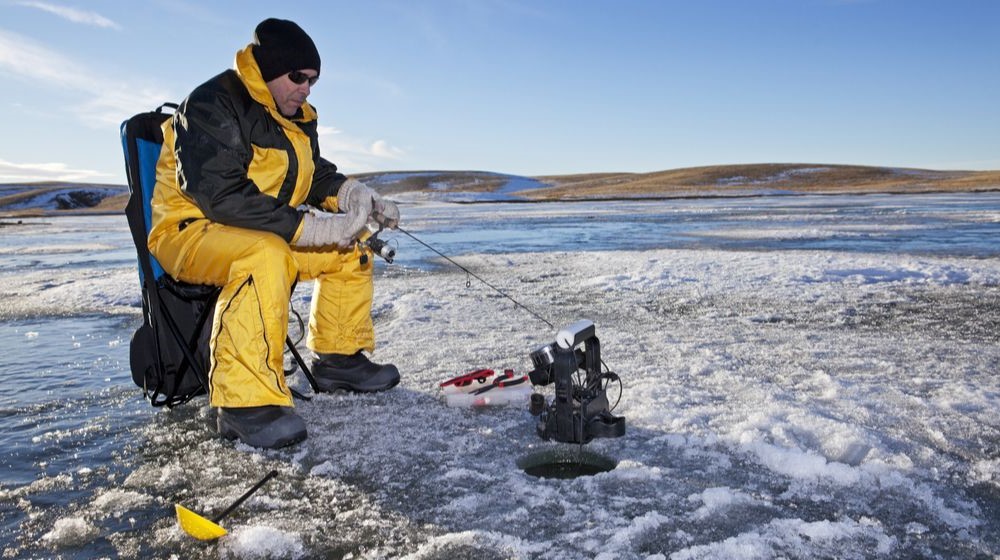 man-ice-fishing-on-frozen-canadian | Ice Fishing Gear Checklist For The Winter Fishermen | Featured