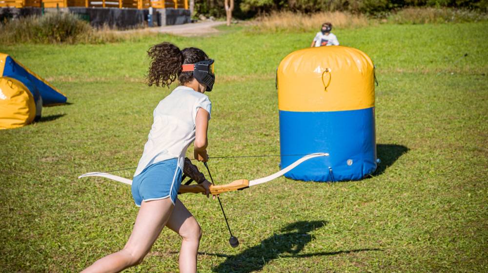 teenage-girl-running-bow-arrow-during | Archery Tag Basics: Getting Started With This Fun Hobby | Featured