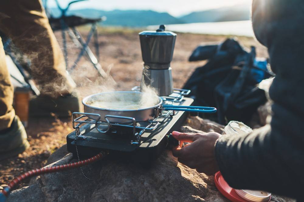 person-cooking-hot-drinks-nature-camping | Best Tent Stoves You Can Bring For Winter Camping | Featured