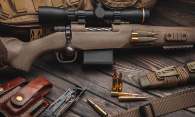 Modern bolted carbine and cartridges for it on a dark wooden table | Best Survival Rifles You Should Own | featured