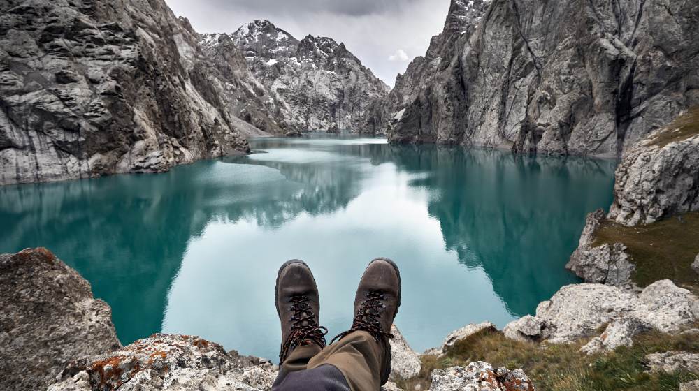 Brown military shoes of hiker in front of mountain lake Kel Suu-hiking boot-ss-featured