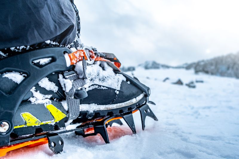 Foot with crampon on boot standing on winter mountain snow-Boot Accessories-ss
