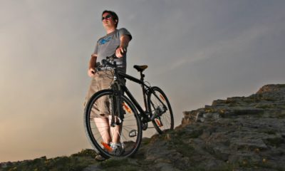 Young Man in Shorts with Hybrid Mountain bike on a rocky hill | How To Buy the Best Hybrid Bike | featured
