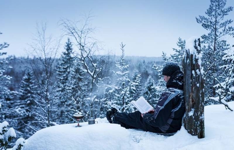 man reading book located on hill | how to prepare for an avalanche