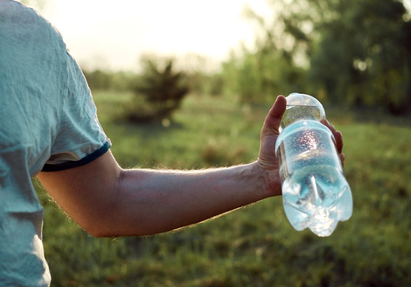 plastic water bottle hand against backdrop | drinking water purification methods